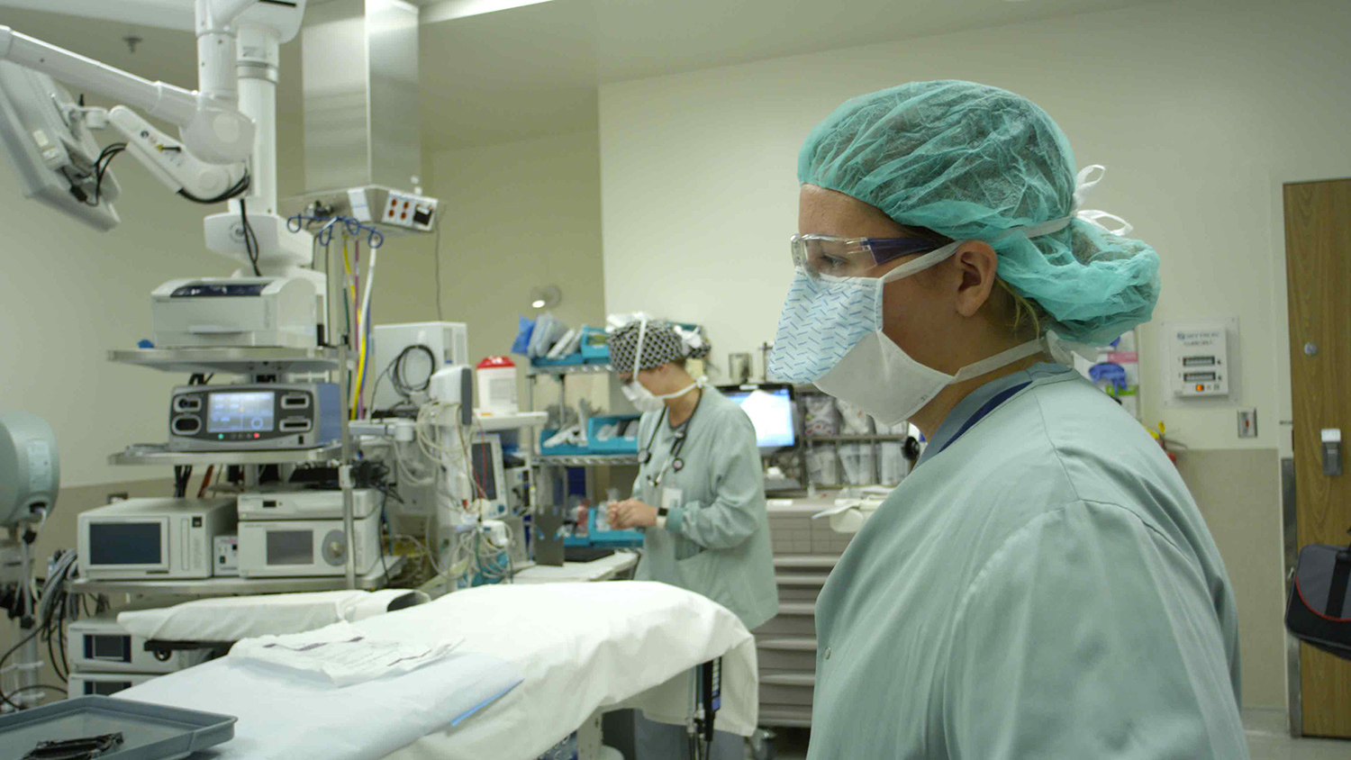 People wearing medical scrubs and masks in a medical examination room