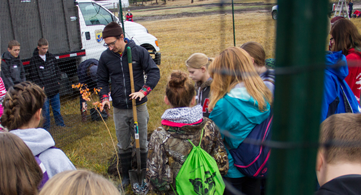 Photo: Man planting tree while students watch