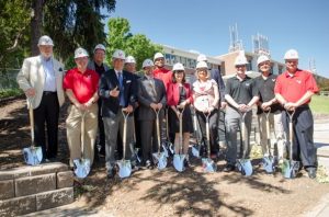 Group poses with shovels at the build site