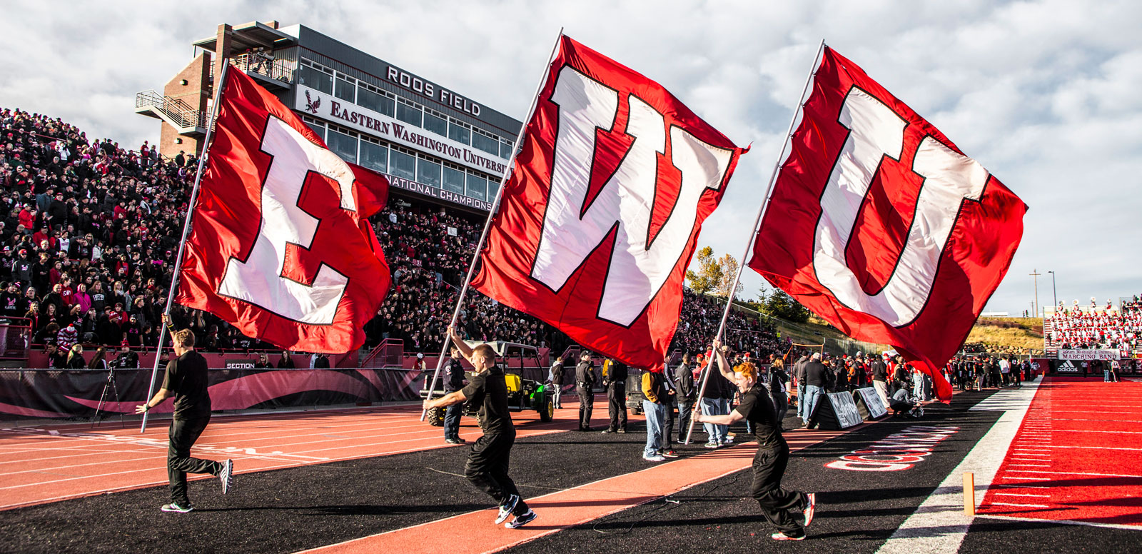 Photo: cheerleaders running with "EWU" flags at Roos Field